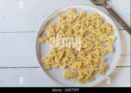 Cooked farfalle or bow tie pasta on a plate on white background Stock Photo