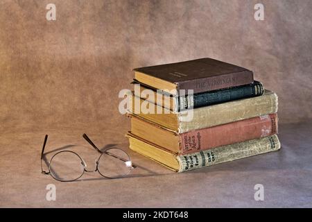 A stack of classic books waiting to be read, including Tarzan of the Apes, The Virginian, Modern Detective Stories, Rogue River Feud, The Wind In The Stock Photo