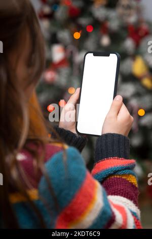 Girl holding a smart phone with the Christmas tree in the background Stock Photo