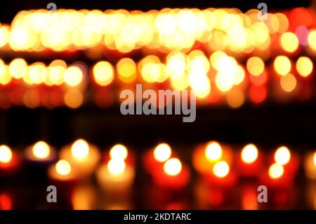 Blurry burning candles in dark church background. Bokeh. Celebration, memorial concepts Stock Photo