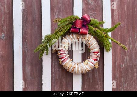 christmas wreath on wooden door fastened in ring and used for decoration with red bow Stock Photo