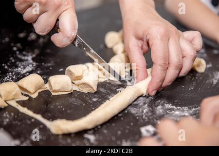 hands cutting dough on the table with a knife Stock Photo