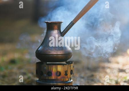 https://l450v.alamy.com/450v/2kdtf9r/making-coffee-process-on-campfire-close-up-coffee-in-turkish-cezve-on-camping-stove-portable-stove-which-burned-wood-chips-2kdtf9r.jpg