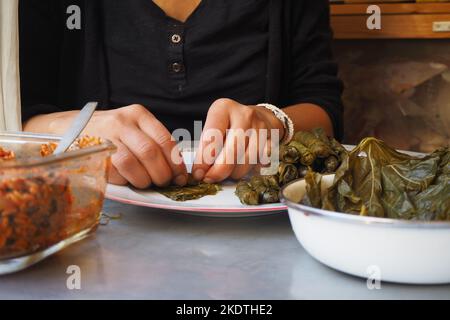 Grape Leaves Stuffed with rice and herbs .Woman preparing wrapped leaf. Stuffed grape leaves ready to cook. Turkish traditional food, Yaprak Sarma. Stock Photo