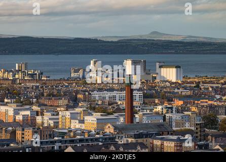 View over rooftops to Firth of Forth, with industrial chimney tower and high rise apartment buildings. Edinburgh, Scotland, UK Stock Photo
