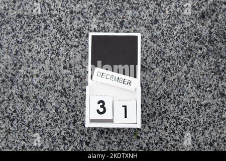 December 31 is written on wooden calendar cubes which lies on a gray stone on the street, Happy New Year, holiday Stock Photo