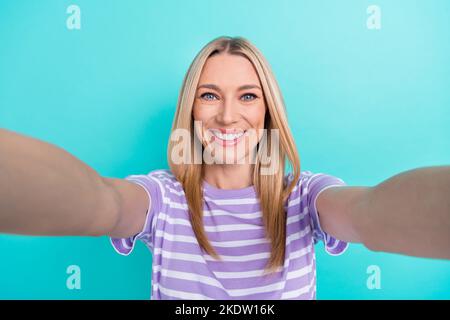 Photo of satisfied glad pleasant woman with straight hairdo dressed striped t-shirt making selfie isolated on blue color background Stock Photo