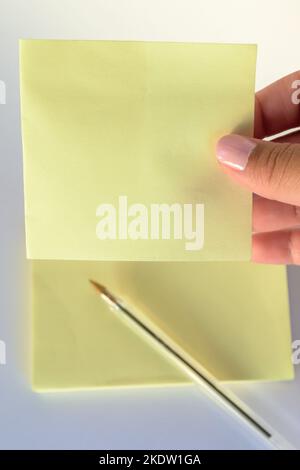 Woman's hand with painted nails holding blank letter paper on pure white background. Stock Photo