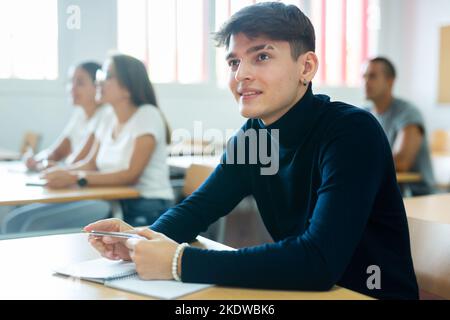 Positive young man attending lecture in college Stock Photo