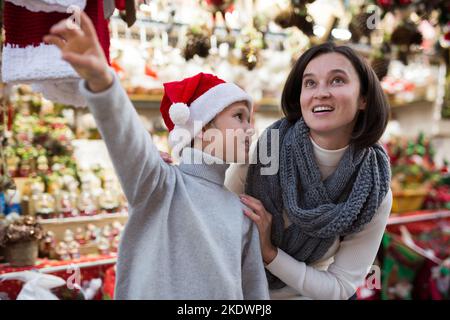 Tween boy with mother choosing Xmas decorations on street fair Stock Photo