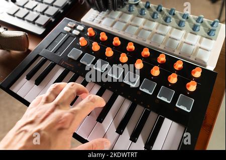 Musician's hand on modern midi keyboard. Close-up. Electronic musical equipment for music studio, recording studio. Artist, musician, composer. Banner Stock Photo