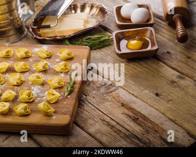 Homemade dumplings on a cutting board. Cooking process. Ingredients on a simple wooden table. Recipes for home and restaurant cuisine. There are no pe Stock Photo