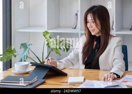 Portrait of a business woman using a tablet computer and calculator for data analysis, marketing, accounting Stock Photo