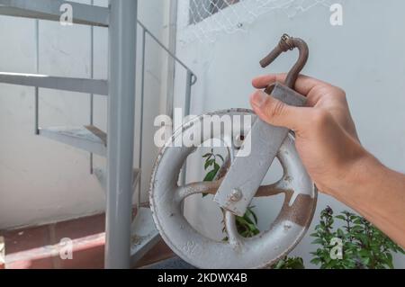 Old pulley made of iron with one hand holding and copy space. Stock Photo