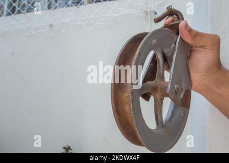 Old pulley made of iron with one hand holding and copy space. Stock Photo