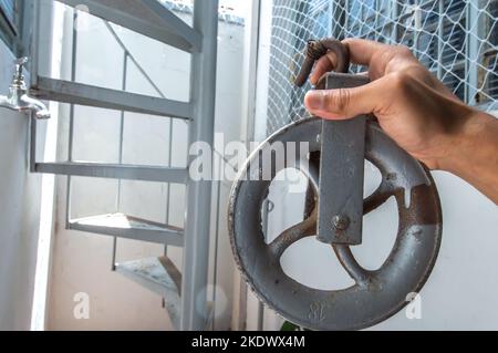 Old pulley made of iron with one hand holding and copy space. Stock Photo