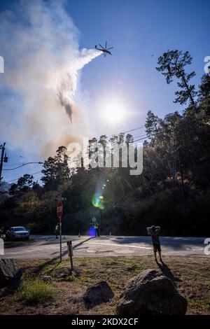 Bystanders and first responders watch as a helicopter drops water on the Aguajito fire in Monterey CA Stock Photo