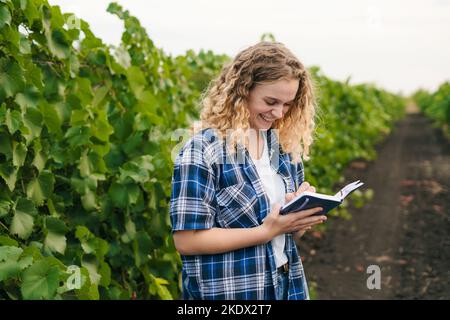 Female field engineer taking notes and analysis to research about vineyard fields problems. Agricultural technology concept. Smart farming concept Stock Photo