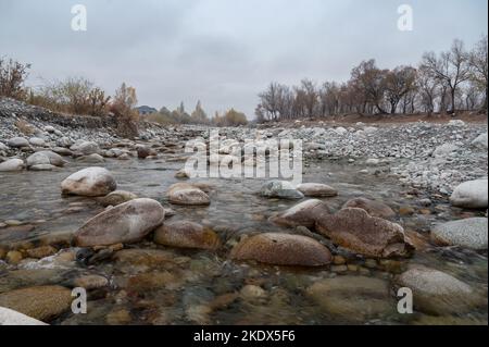 Slow and not deep mountain river with rounded stones Stock Photo