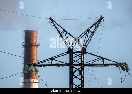 Lattice-type steel overhead power line tower and power plant chimney are under  blue sky Stock Photo