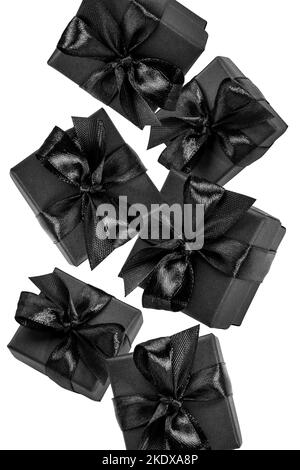 Black wrapped gift boxes decorated with black ribbons and bows falling on white. Black present boxes isolated on white. Black friday, shopping, Boxing Stock Photo