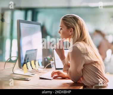 Fully focused on her work. a focused young businesswoman working on a computer in an office. Stock Photo