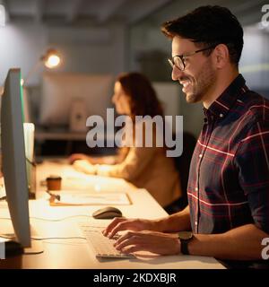 The internet never sleeps. two businesspeople using their computers while working overtime in the office. Stock Photo