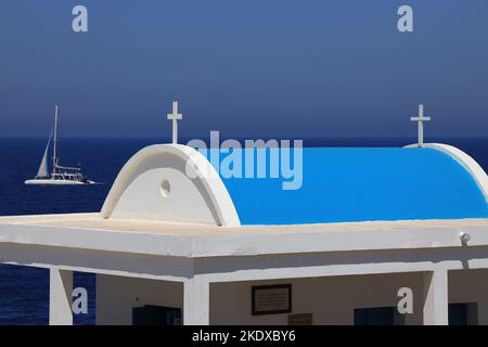 May 26, 2022, Larnaca, Cyprus: Sail boat passes behind The Agioi Anargyroi church at Cape Greco, sits at the edge of a vertical rock cliff above the sea. It is dedicated to Saints Kosmas and Damianos. Below the chapel there is a cave with the holy water of the Saints. The Republic of Cyprus stands at a historic and cultural crossroads between Europe and Asia. Its chief cities-the capital of Nicosia, Limassol, Famagusta, and Paphos have absorbed the influences of generations of conquerors, pilgrims, and travelers and have an air that is both cosmopolitan and provincial. (Credit Image: © Ruaridh Stock Photo