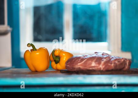 fresh meat and yellow peppers in a blue kitchen Stock Photo