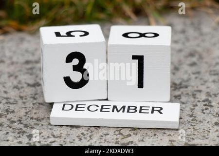 December 31 is written on wooden calendar cubes which lies on a gray stone on the street, Happy New Year, holiday Stock Photo
