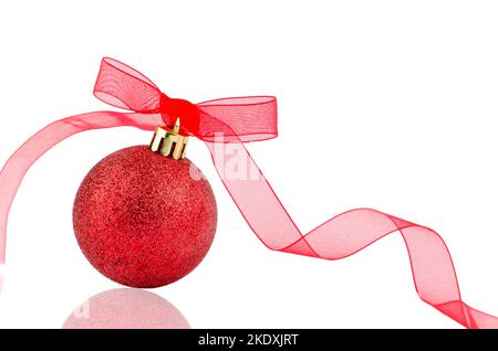 Red Christmas ball tied with a red ribbon isolated on a white background. New Year and Christmas toys. Christmas paraphernalia. Stock Photo