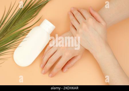 Women's hands and a white tube of moisturizer on a beige background. Organic cosmetics for skin care. Beauty concept Stock Photo