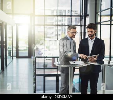 Lets move forward on this. two businessmen looking over a tablet in the office. Stock Photo