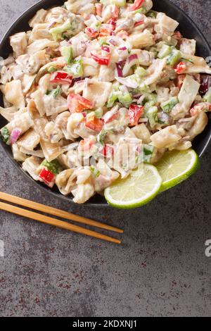 Closeup of Dinakdakan made with strips of pig ears, liver and face with vegetables on the plate on the table. Vertical top view from above Stock Photo