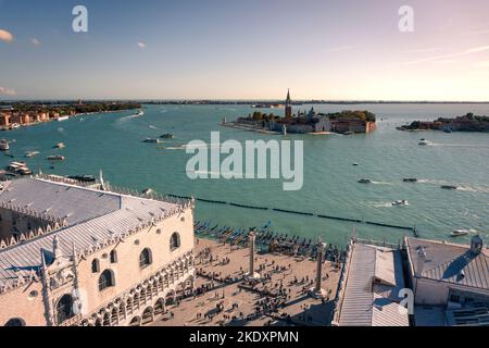 High angle drone view of crowded Piazza San Marco and San Giorgio Maggiore island located near water with fast boats at sunset in Venice, Italy Stock Photo