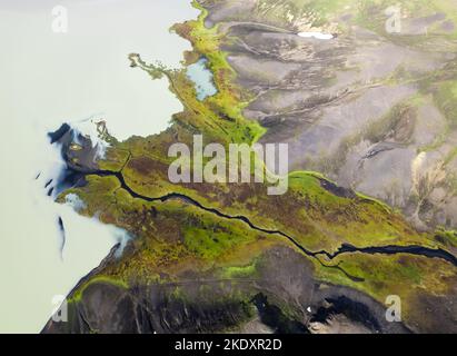 Picturesque drone view of curvy river flowing from white glacier in green valley near mountains in Iceland Stock Photo