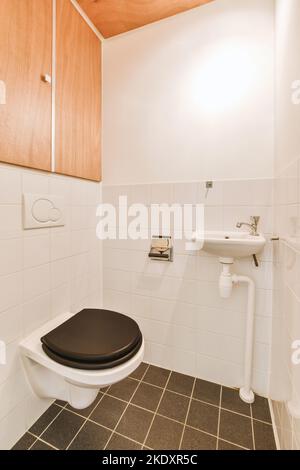 Wall hung toilet and small sink in corner in lavatory room Stock Photo
