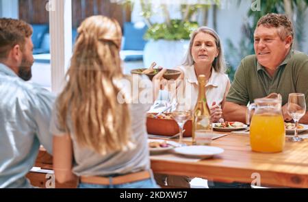 Family, food and eating people with champagne, lunch and outdoor patio for holiday, celebration or reunion BBQ. Family grandparents with table food Stock Photo