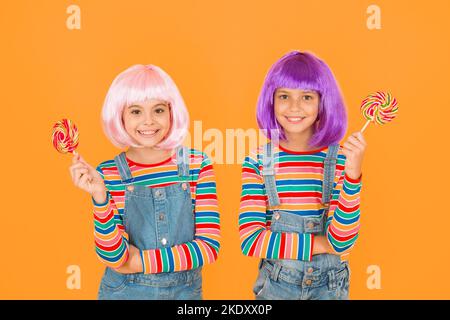 Anime cosplay party concept. Happy little girls. Anime fan. Kids with artificial hairstyles eating lollipops. Anime convention. Vibrant characters Stock Photo