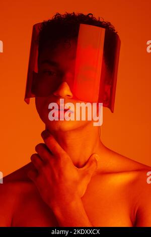 Orange, futuristic and man with a neon visor for cyberpunk, creative style and art against a studio background. Digital, fashion and face portrait of Stock Photo