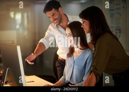 They make brainstorming look easy. a group of colleagues brainstorming around a computer in the office. Stock Photo