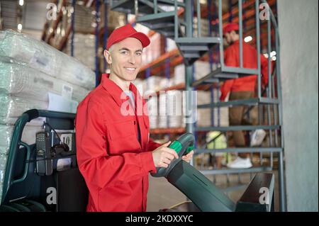 Cheerful lift truck operator and his colleague in the warehouse Stock Photo