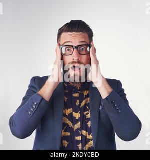 Oh my goodness. Portrait of a surprised young man holding on to his glasses in studio. Stock Photo