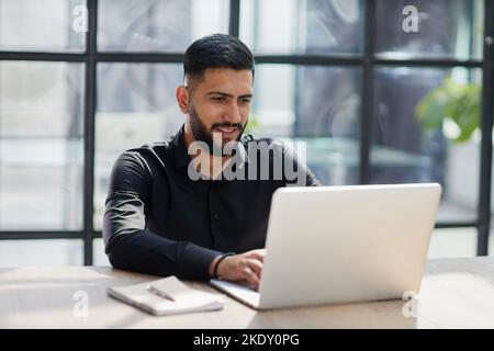Bearded young businessman working on modern office. Consultant man thinking looking in monitor computer Stock Photo