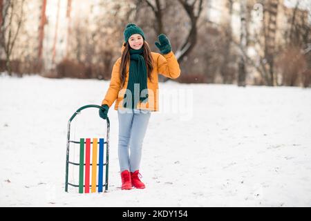 Full body portrait of young woman walking in snowy winter park
