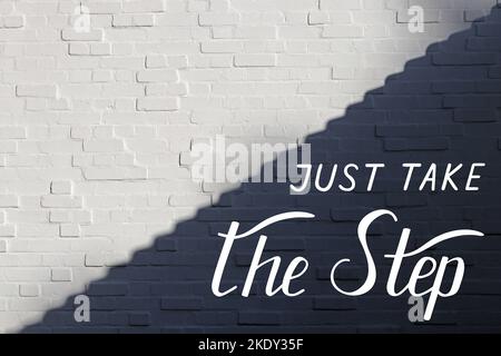 Just take the step - individual handwritten lettering on white brick wall, divided into light and shadow parts along the diagonal in form of steps. Stock Photo