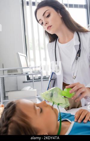 Pediatrician holding oxygen mask and looking at patient in clinic,stock image Stock Photo