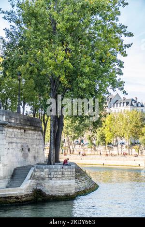 Paris, France - 09-12-2018:  sitting girl studies on the bank of the Seine in Paris Stock Photo