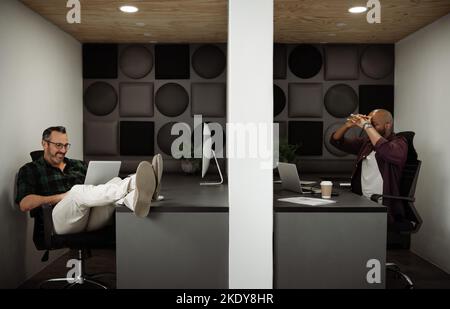 Two freelance business men working in cubicle styled co working office space. Stock Photo