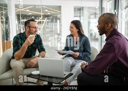 Casual meeting of smiling diverse business team analyzing financial data. Group team discussion in office lobby Stock Photo